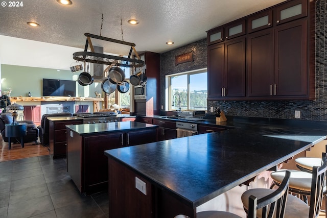 31367 Clarks Creek Rd, Mount Vernon, OR 97865 - kitchen with dark countertops, a peninsula, a center island, dark brown cabinets, and a sink