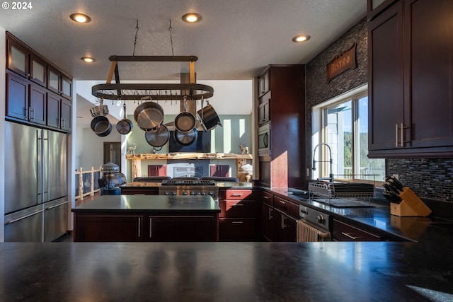 kitchen with kitchen peninsula, dark brown cabinets, a textured ceiling, and appliances with stainless steel finishes