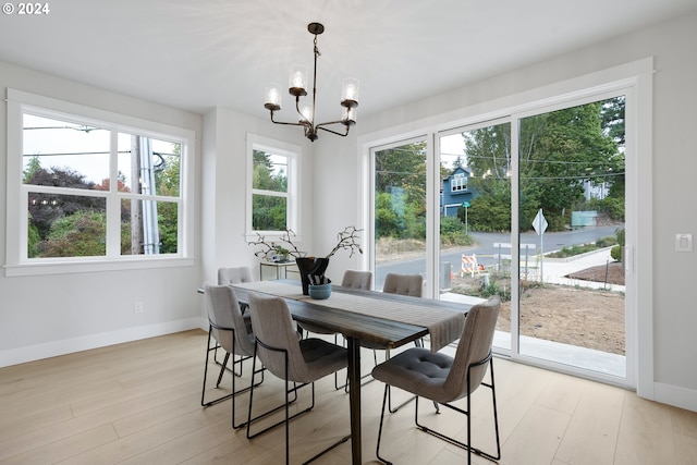 dining space featuring light wood-type flooring, a wealth of natural light, and a chandelier