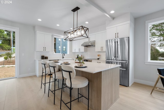 kitchen featuring stainless steel fridge, a healthy amount of sunlight, hanging light fixtures, and a center island