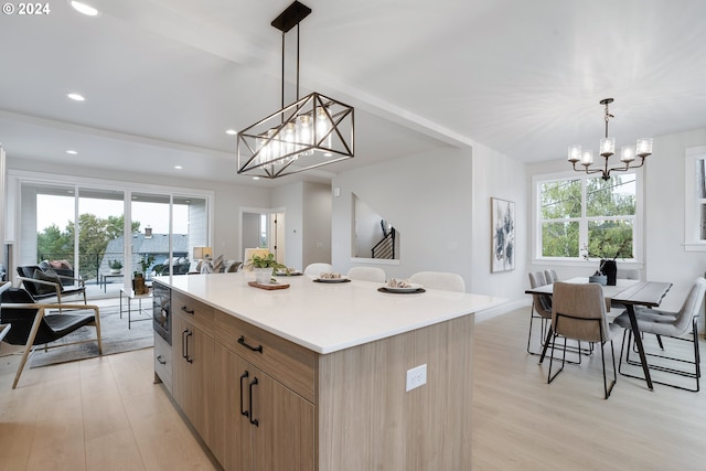 kitchen featuring plenty of natural light, decorative light fixtures, a kitchen island, and light wood-type flooring