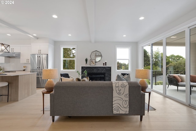 living room with a fireplace, beamed ceiling, and light hardwood / wood-style flooring