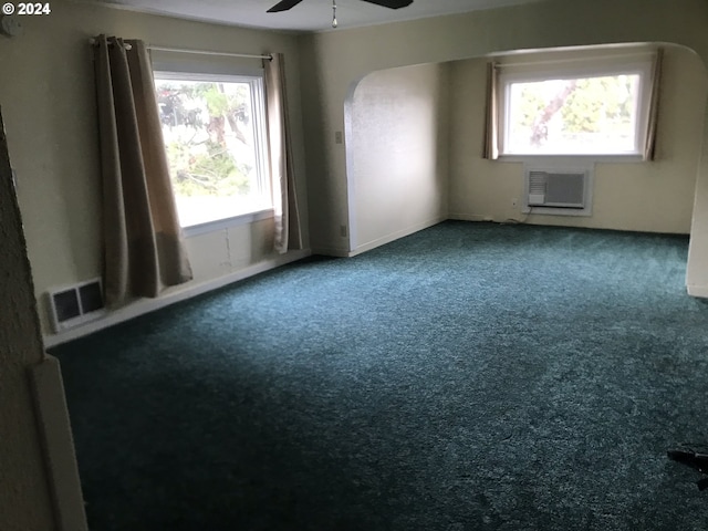 carpeted empty room with a wall unit AC and ceiling fan