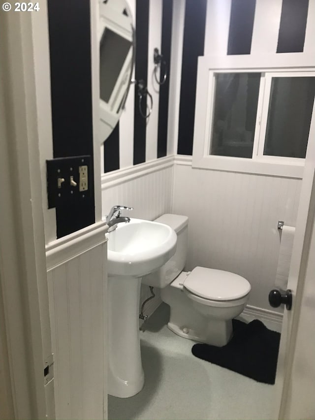 bathroom featuring wooden walls and toilet