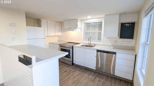 kitchen with sink, white cabinetry, light wood-type flooring, appliances with stainless steel finishes, and decorative backsplash