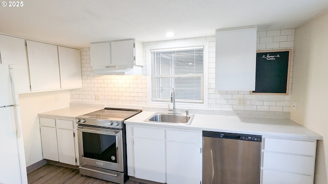 kitchen with dark wood-type flooring, sink, appliances with stainless steel finishes, white cabinets, and backsplash