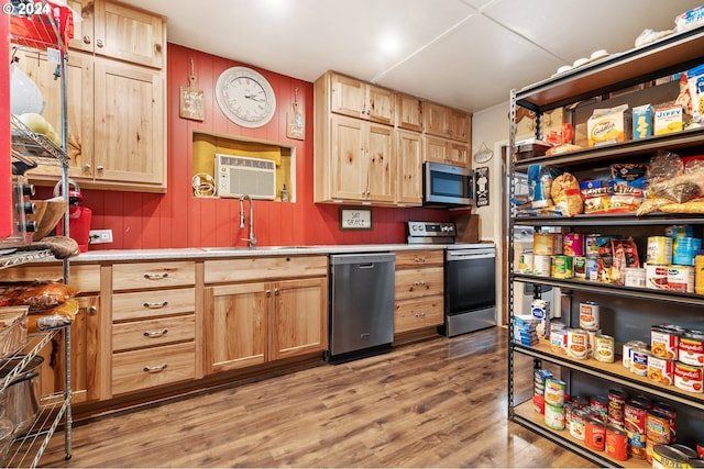 kitchen with a wall unit AC, hardwood / wood-style floors, stainless steel appliances, and sink