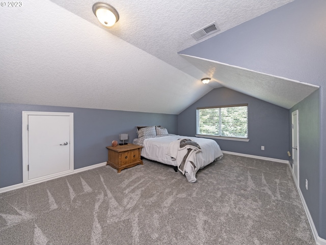 bedroom with a textured ceiling, carpet, and lofted ceiling