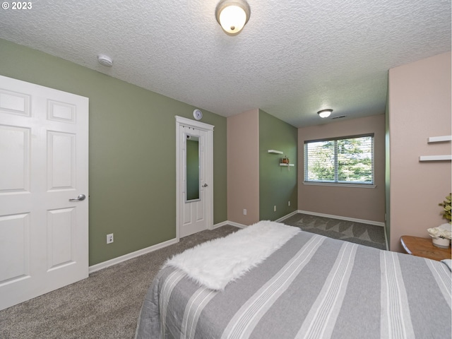 bedroom featuring a textured ceiling and dark carpet