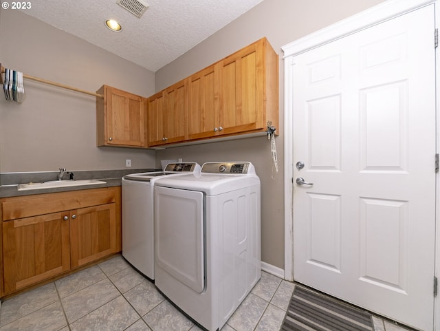 clothes washing area featuring separate washer and dryer, a textured ceiling, cabinets, sink, and light tile patterned flooring