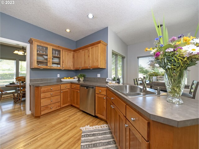 kitchen featuring dishwasher, light hardwood / wood-style floors, kitchen peninsula, sink, and a textured ceiling