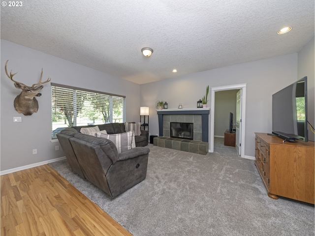 living room featuring a textured ceiling, a tiled fireplace, and carpet flooring