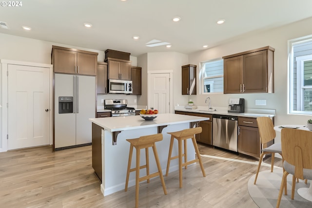 kitchen with a kitchen breakfast bar, a center island, stainless steel appliances, and light wood-type flooring