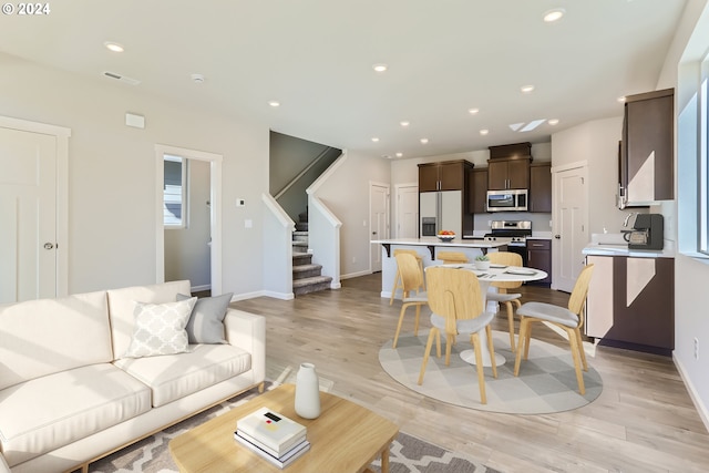 living area with recessed lighting, baseboards, stairway, and light wood finished floors