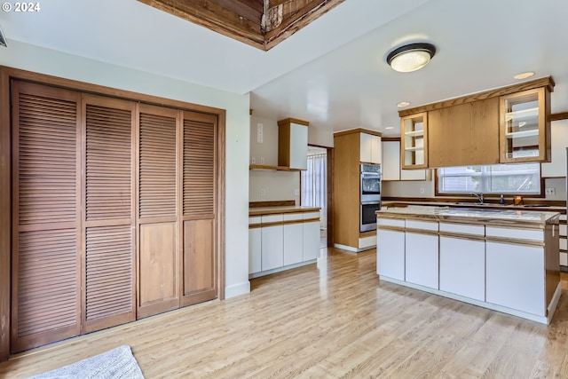 kitchen featuring white cabinetry, double oven, and light hardwood / wood-style floors