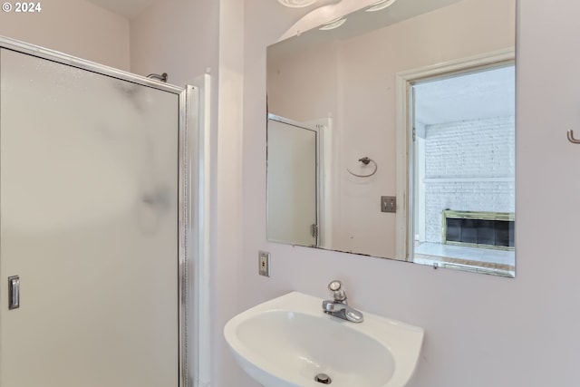 bathroom with a fireplace, walk in shower, and sink