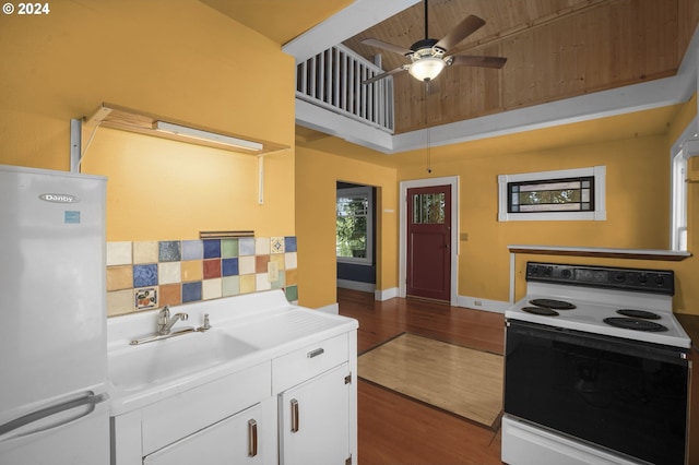 kitchen with hardwood / wood-style floors, white appliances, white cabinets, ceiling fan, and a towering ceiling