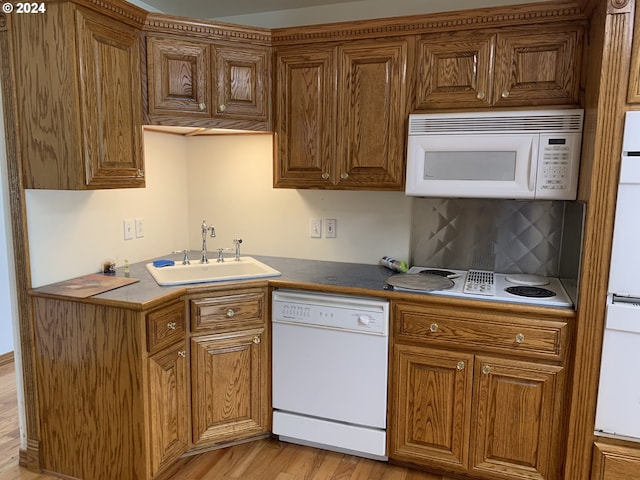 kitchen with white appliances, decorative backsplash, sink, and light hardwood / wood-style flooring