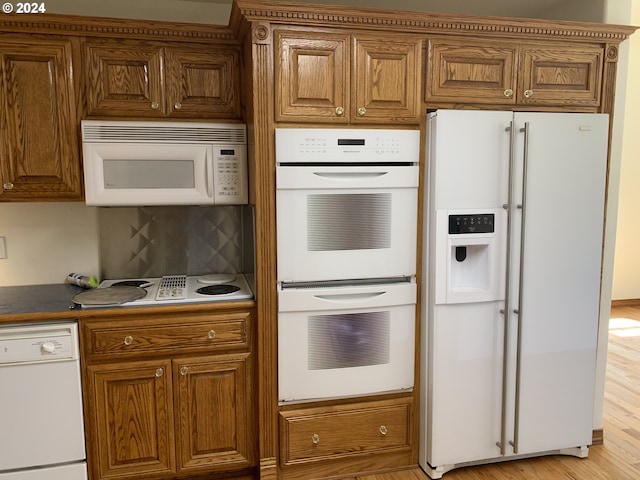 kitchen featuring white appliances, decorative backsplash, and light hardwood / wood-style floors