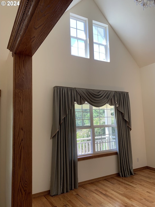 spare room with lofted ceiling, plenty of natural light, and light hardwood / wood-style floors