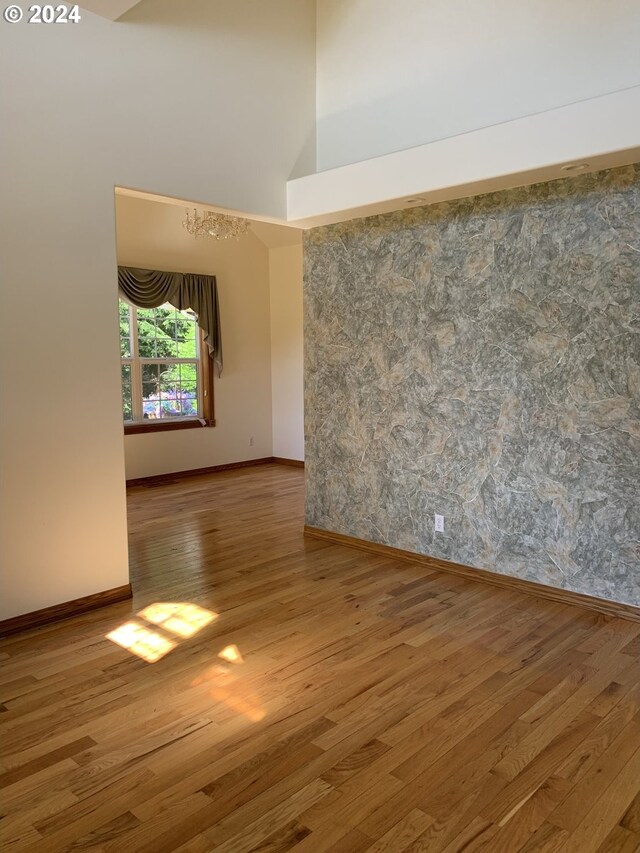 unfurnished room featuring a towering ceiling and hardwood / wood-style flooring