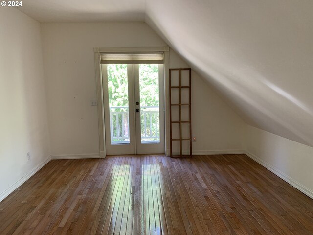 additional living space featuring lofted ceiling, plenty of natural light, french doors, and dark hardwood / wood-style flooring