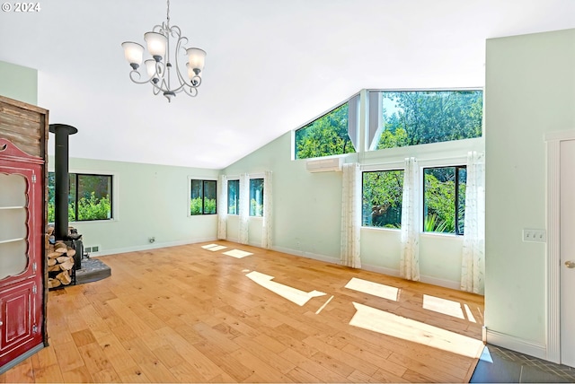 unfurnished living room featuring light hardwood / wood-style flooring, high vaulted ceiling, an AC wall unit, a chandelier, and a wood stove