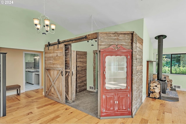 hallway featuring a barn door, lofted ceiling, a notable chandelier, and light wood-type flooring