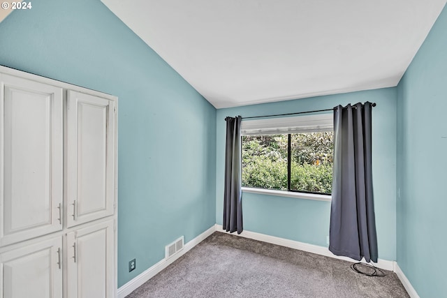 carpeted empty room featuring vaulted ceiling