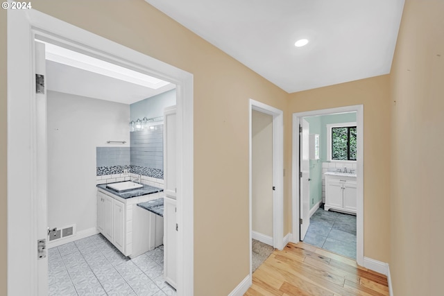 hallway with sink and light hardwood / wood-style flooring