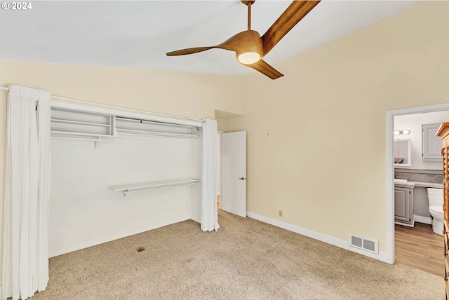 unfurnished bedroom featuring ceiling fan, connected bathroom, light colored carpet, and vaulted ceiling with beams