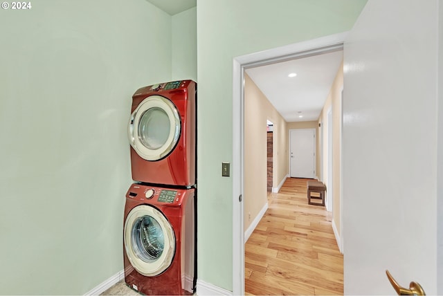 laundry area featuring stacked washer and clothes dryer and light wood-type flooring