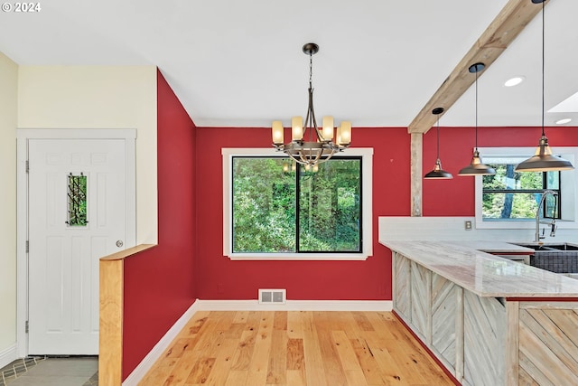 dining room with an inviting chandelier, sink, light hardwood / wood-style floors, and beamed ceiling