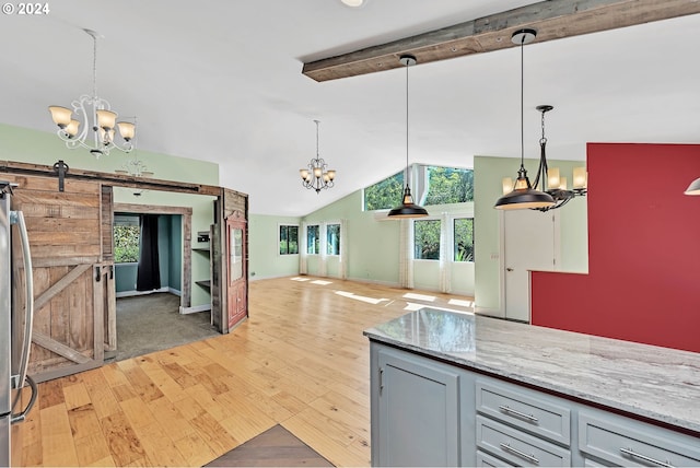 kitchen with pendant lighting, gray cabinets, vaulted ceiling with beams, a barn door, and light wood-type flooring