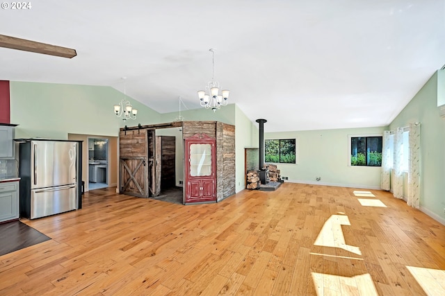 kitchen featuring decorative light fixtures, stainless steel fridge, light hardwood / wood-style floors, a barn door, and an inviting chandelier