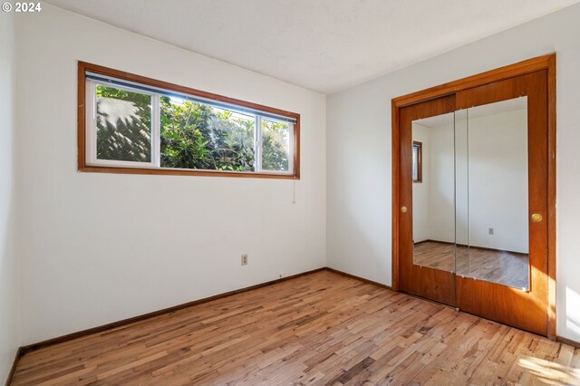 unfurnished bedroom with light hardwood / wood-style flooring and a closet