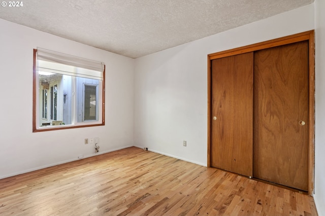 unfurnished bedroom with light wood-type flooring, a textured ceiling, and a closet