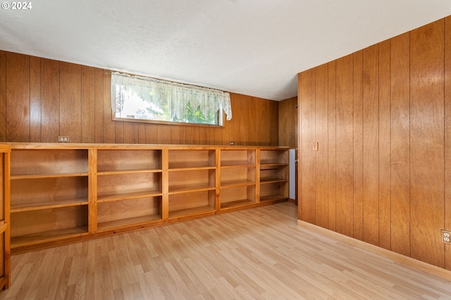 basement featuring light hardwood / wood-style flooring and wood walls