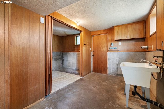 bathroom featuring wooden walls, sink, and concrete floors