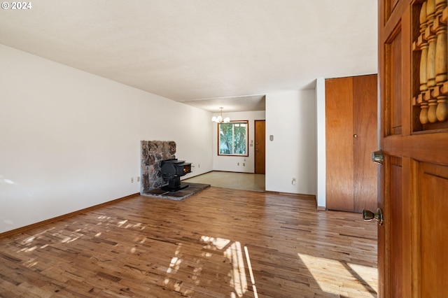 unfurnished living room with a chandelier, hardwood / wood-style flooring, and a wood stove