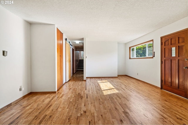 entryway with a barn door, light wood-type flooring, and a textured ceiling