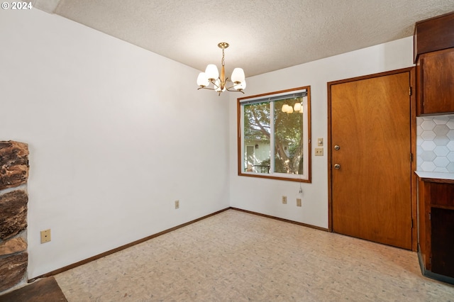 unfurnished dining area with a textured ceiling and a notable chandelier