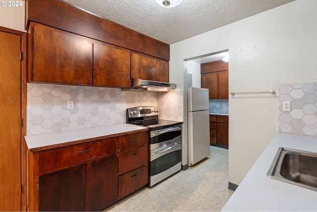 kitchen featuring sink, range hood, white fridge, decorative backsplash, and stainless steel range with electric cooktop