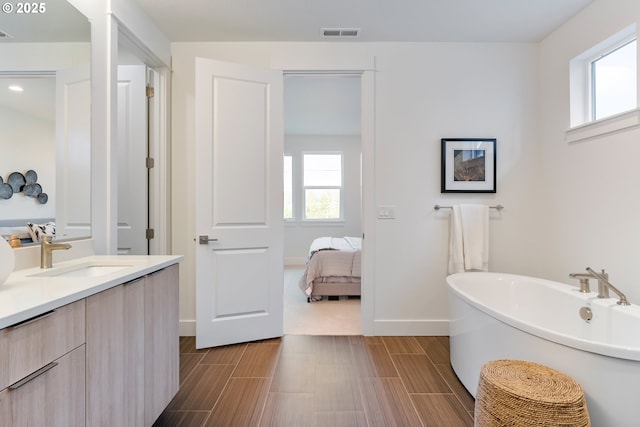 bathroom with a tub to relax in, vanity, and a wealth of natural light