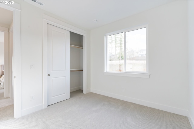 unfurnished bedroom with light carpet and a closet