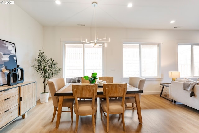 dining area featuring a healthy amount of sunlight, an inviting chandelier, and light hardwood / wood-style flooring