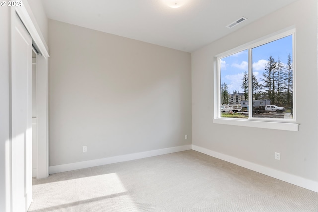 unfurnished bedroom with light colored carpet and a closet