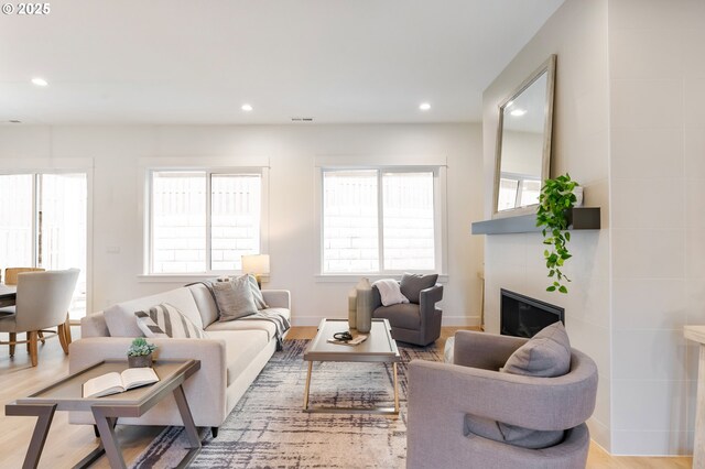 kitchen featuring light hardwood / wood-style floors, appliances with stainless steel finishes, white cabinetry, backsplash, and a center island with sink