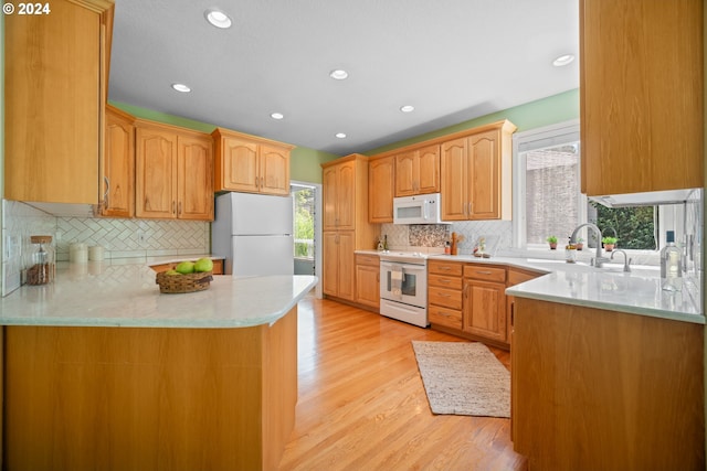 kitchen featuring light hardwood / wood-style flooring, white appliances, a wealth of natural light, and kitchen peninsula