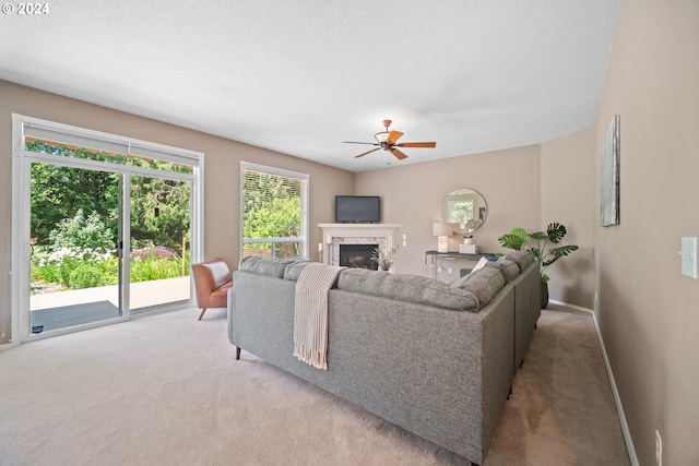 carpeted living room with ceiling fan, a textured ceiling, and a fireplace